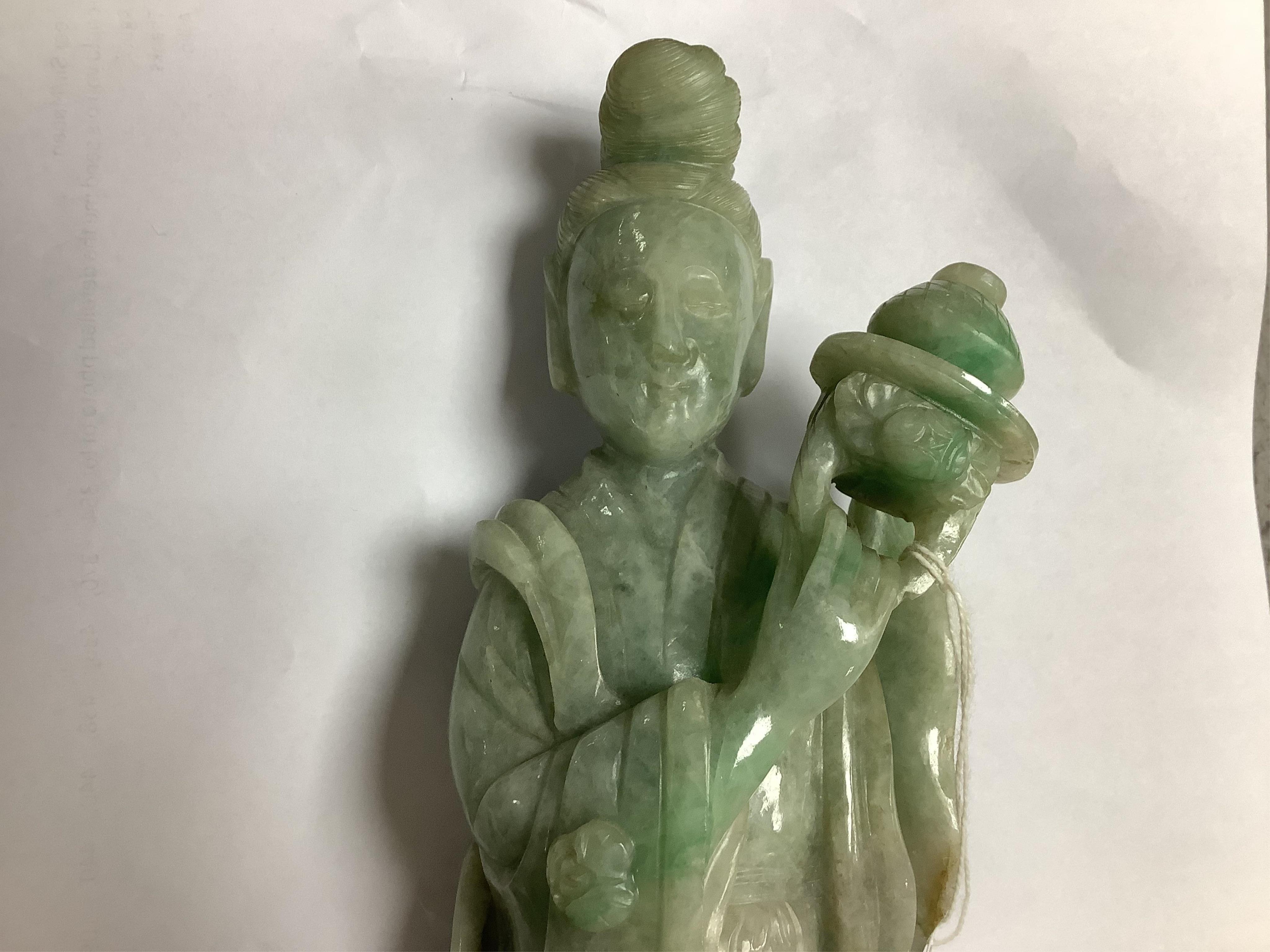 A Chinese jadeite carving of Guanyin, on associated hardwood stand, 38cm high. Condition - fair